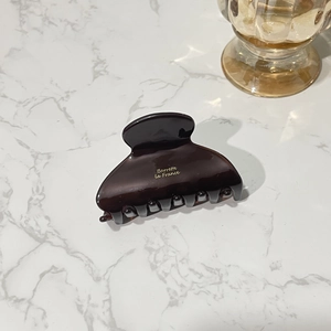 Detail of dark brown tortoiseshell acetate hair claw clip on white marble surface