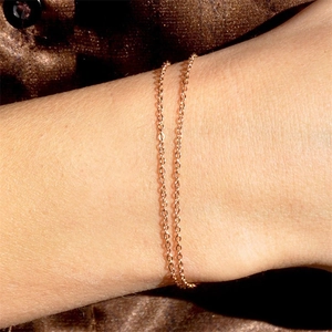 Minimalist double layered gold chain bracelet for women on an elegant brown silk background
