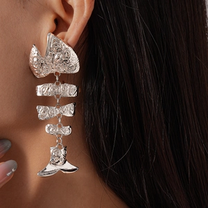 Detailed close-up of a silver articulating fishbone earring worn by a model