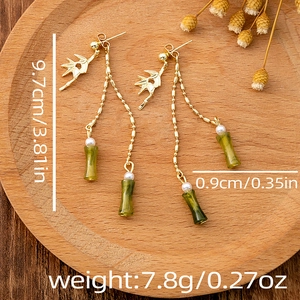 Detailed view of long bamboo leaf tassel earrings with green resin and white pearls