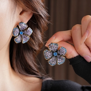 Gros plan détaillé des boucles d'oreilles fleurs vintage avec cristaux violets et bleus