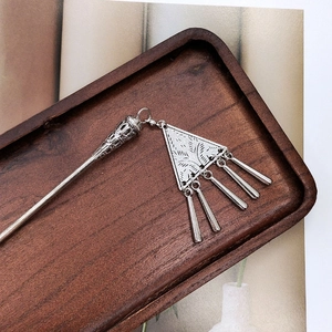 Detailed close-up of Miao silver hair stick with ornate carvings and tassel pendants