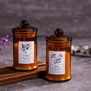 Eucalyptus and vanilla scented candles in amber glass jars on a rustic wood tray