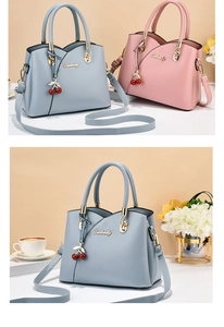 Detail of blue and pink PU leather handbags with cherry charms and branded metal logo