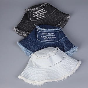 Dettaglio di cappelli pescatore in denim con bordi sfrangiati e ricami in tre colori