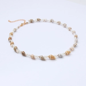 Detail view of conch shell and white bead necklace with adjustable gold chain