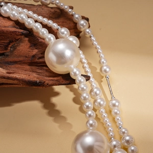 Vue détaillée d'un collier de perles baroques multicouches sur un socle en bois naturel