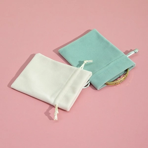 Detail view of plush drawstring jewelry pouches in beige and mint green colors