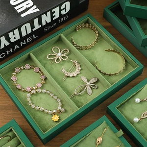 Green velvet jewelry display tray for organizing gold pearl hairpins and bracelets