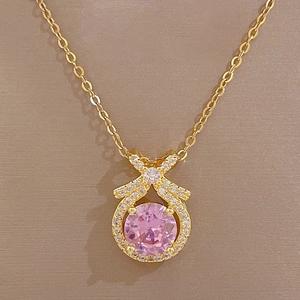 Close-up of golden bow pendant with a round pink stone and sparkling micro-diamonds