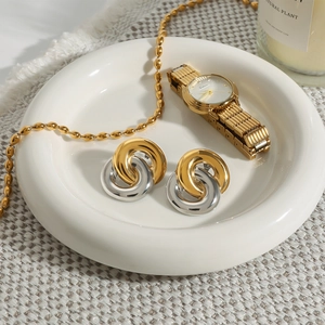 Close-up of interlocking two-tone earrings in gold and silver on a white plate