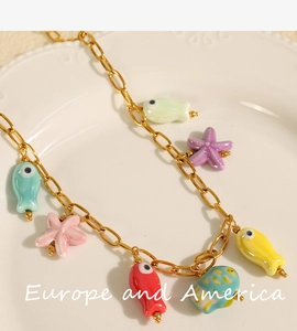 Detailed close-up of golden necklace with colorful ceramic ocean charms and sea stars