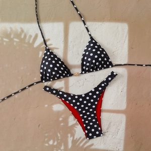 Close-up of polka dot bikini top with a golden sun buckle against a palm shadow background