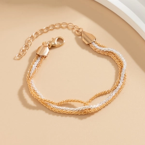 Close-up of triple-strand woven gold and silver chain bracelet with lobster clasp