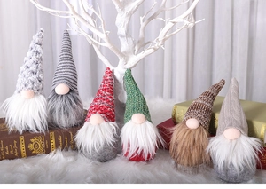Close-up of knit Christmas gnomes in various colors on white faux fur with decor