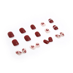 Red and pink press-on nails with hand-painted floral designs and pearl decorations