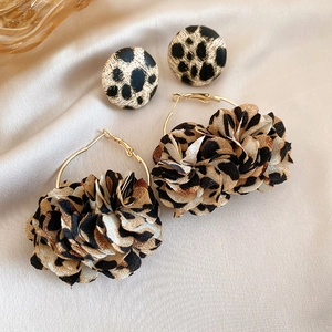 Detailed macro view of leopard print fabric petals and gold hoop earrings on satin