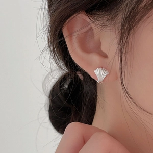 Primo piano di un orecchino a conchiglia in argento dallo stile minimalista