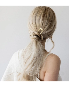 Detailed view of a gold U-shaped metal hairpin worn in a stylish bun hairstyle