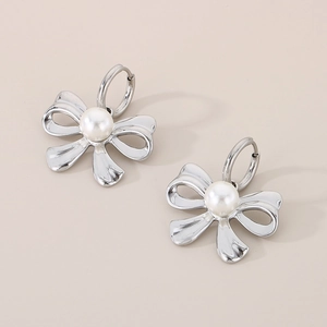 Detail shot of silver bow earrings with center pearl inlay on a beige background