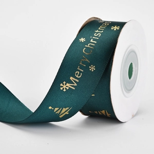 Detail of dark green Christmas ribbon with gold Merry Christmas print and snowflakes