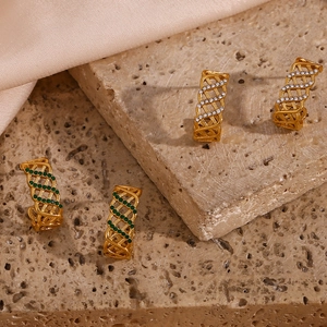 Détail de boucles d'oreilles en C évidées avec cristaux verts et blancs sur pierre texturée