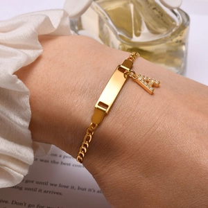 Close-up of gold stainless steel ID bracelet with crystal letter A charm on wrist