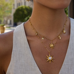 Detail of double-layered 18K gold plated sun pendant necklace with white opal stone on a model