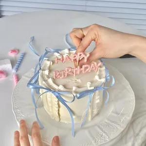 Hand decorating a minimalist cream cake with blue ribbons and pink birthday topper