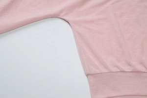Detailed close-up showing the precise underarm stitching of this pink knit sheer top