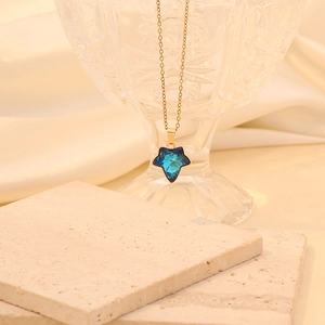 Gros plan d'un pendentif en cristal étoile bleue sur chaîne dorée et tissu en soie