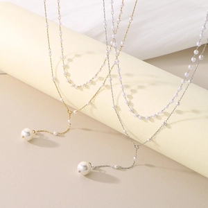 Detail of elegant Y-shaped pearl tassel necklaces in gold and silver on a pedestal