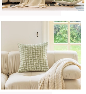 Detail of green houndstooth pillow cover on beige leather sofa with knit blanket