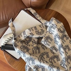 Close-up of canvas tote bag with sheep pattern on a wooden tray in a cozy home setting