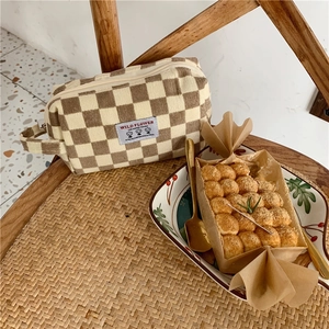 Détail de la trousse cosmétique en velours côtelé à damier avec poignée latérale