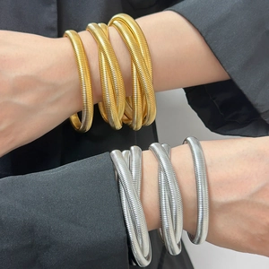 Elegant gold and silver spring coil bracelets worn on wrist in a stylish stacked metal look
