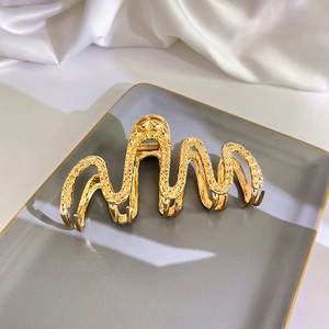 Makroaufnahme einer großen goldenen Haarspange aus Metall mit Blumenrelief auf Satin
