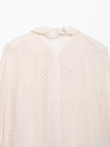 Detail of ruffle stand collar and delicate polka dot chiffon fabric on beige blouse