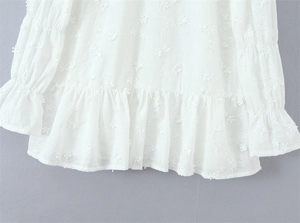 Detailopname van witte chiffon blouse met bloemenborduursels en ruches afwerking