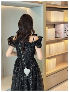 Rear view of elegant black sequin dress paired with a sparkling heart-shaped diamond bag