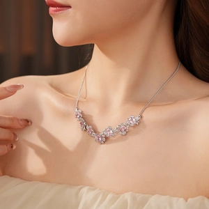 Macro shot of silver necklace with pink gemstones and clear zircons on female neck