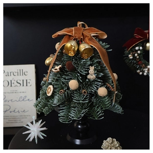 Close-up of mini handmade Christmas tree with brown velvet bow and golden bell decoration