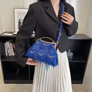 Close-up of blue sequin evening bag with fringe tassels held by model in black suit