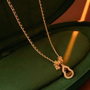 Macro shot of gold gourd pendant with tiger eye stone and zircons in a velvet box