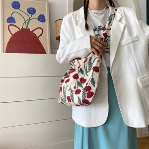 Detailed shot of large off-white canvas tote bag with red poppy print on a female model