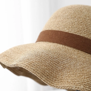 Detailed macro view of woven straw sun hat texture with brown decorative ribbon accent