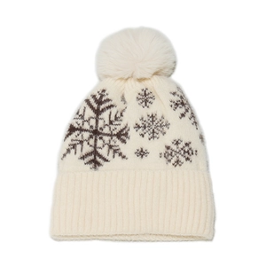 Close-up of cream knit winter beanie featuring brown snowflake patterns and faux fur pom