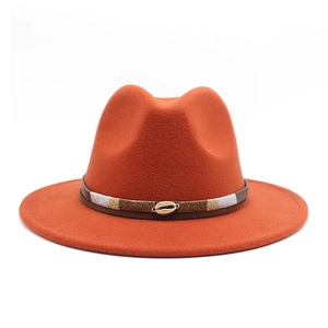 Close-up of orange fedora with leather band and golden cowrie shell ornaments