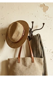 Detail of vintage cast iron coat hook with hat, bag and scarf on rustic wall