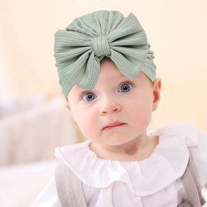 Close-up of sage green ribbed knit baby turban featuring an oversized decorative bow